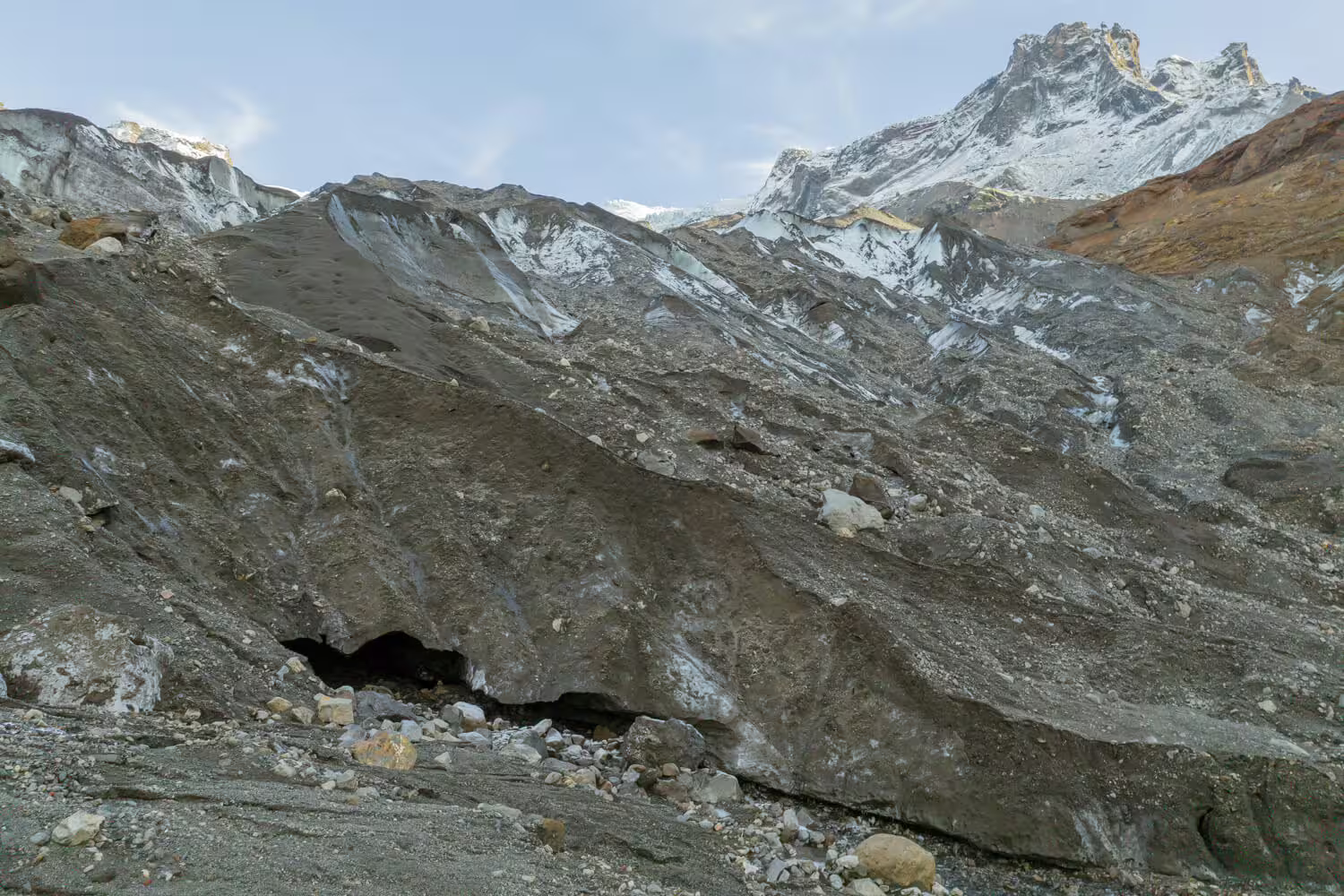 Close-up of ash-layered glacial ice surface with small cave opening during Krossarjokull Glacier citizen science tour in Iceland