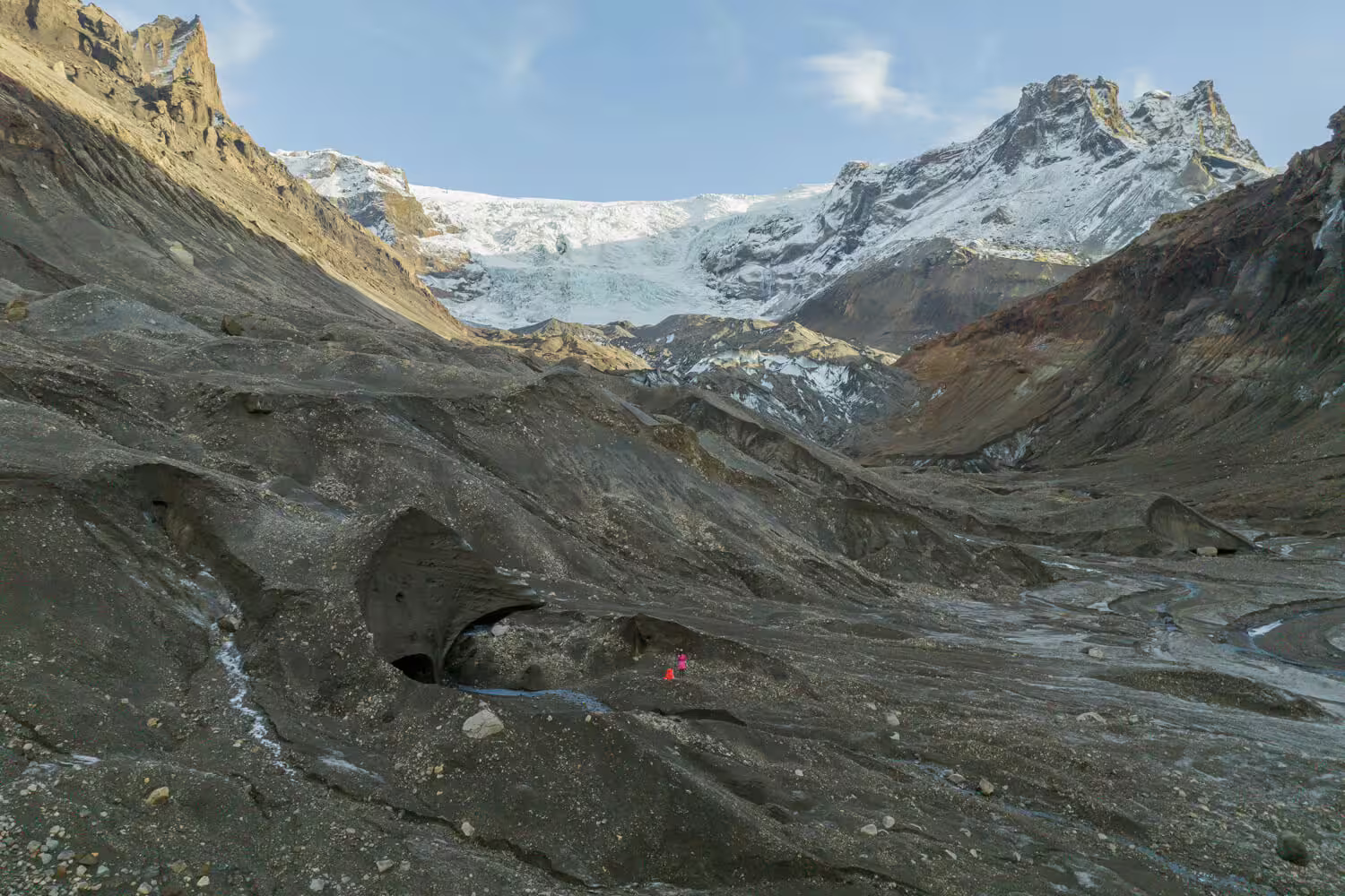 Panoramic view of Krossarjokull Glacier valley with hiker on volcanic black ice during an immersive citizen science day trip