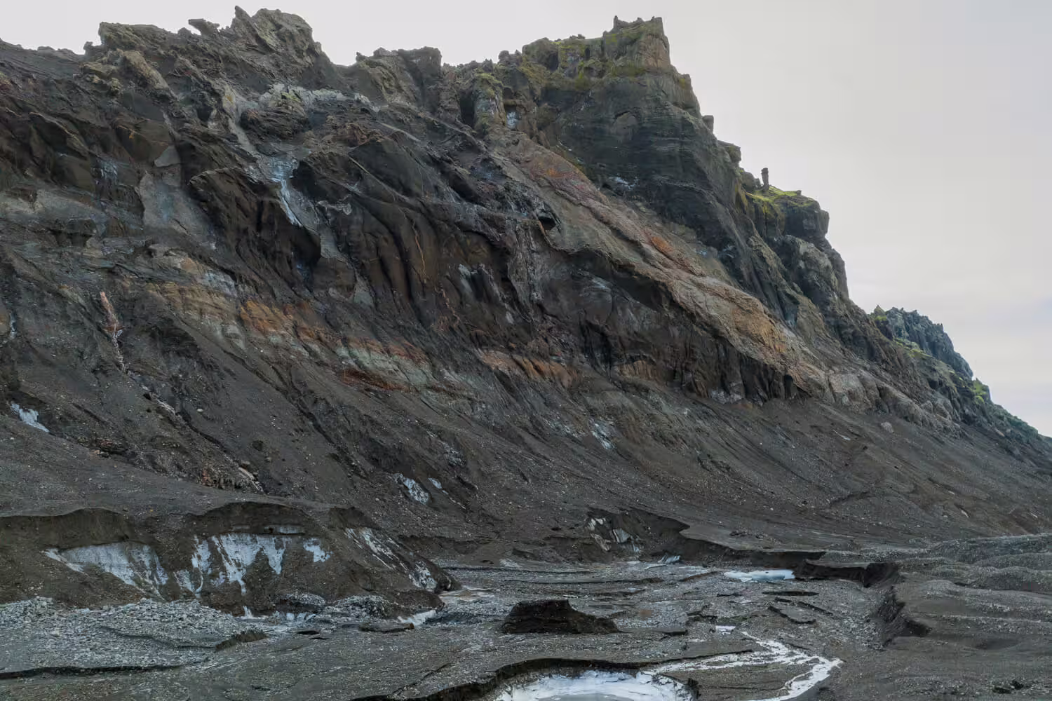 Rugged volcanic rock face with ice patches near Krossarjokull Glacier Iceland citizen science day trip