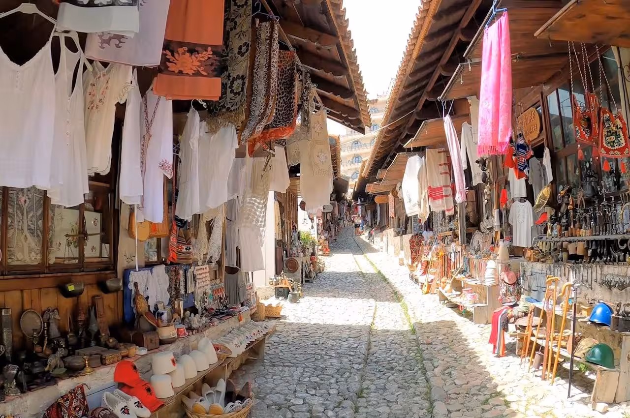 Charming bazaar in Kruje featuring traditional clothing, crafts, and souvenirs on a cobblestone street.