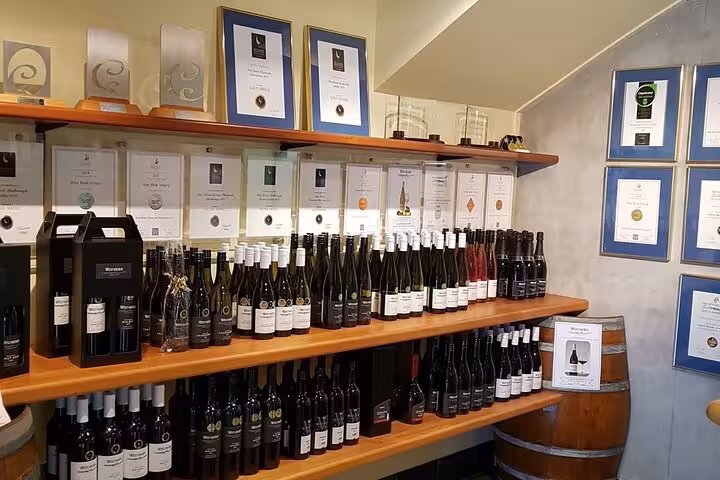Selection of award-winning wines and certificates on display at Kumeu Wine Tour showcasing excellence.