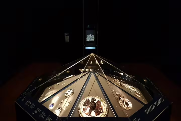 Illuminated display of ancient artifacts in a dimly lit exhibit at the Kunsthistorisches Museum, Vienna.