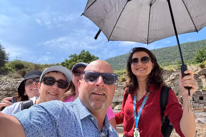 Kusadasi cruise shore tour group at Ephesus with local guide holding umbrella, heading to Virgin Mary’s House