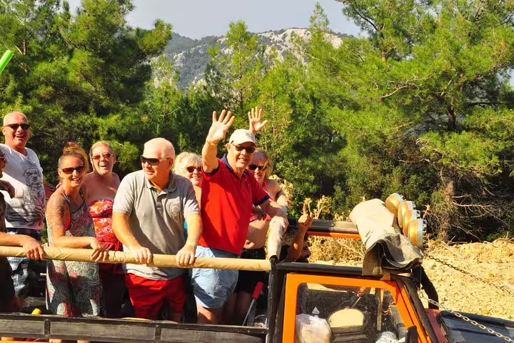 Group of tourists enjoying scenic views on open-top jeep tour in Kusadasi national park.