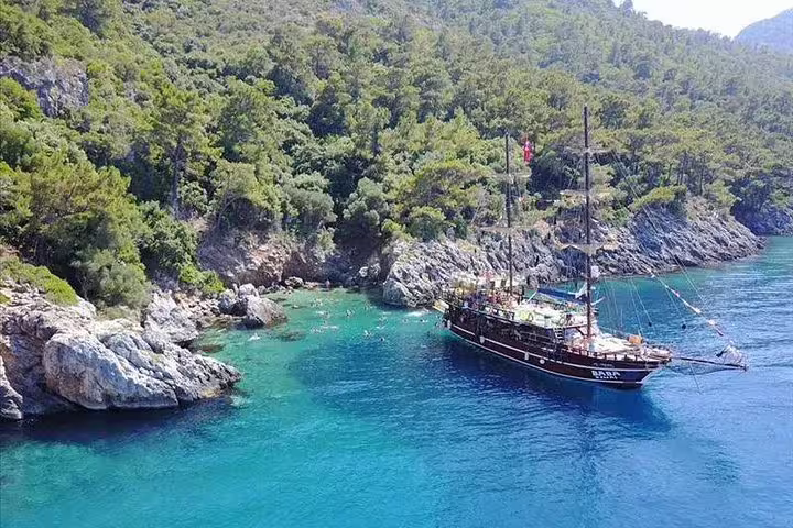 Serene boat anchored near lush forested coastline during Kusadasi National Park boat tour.