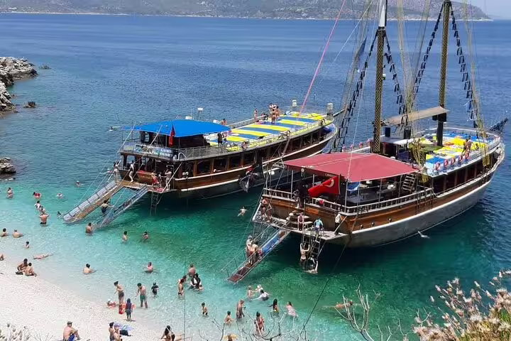 Scenic boat trip along Kusadasi coast with tourists enjoying crystal-clear waters and beach activities.