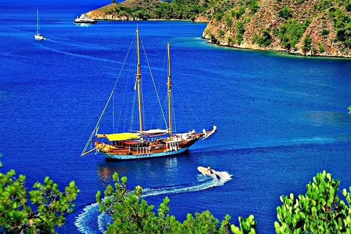 Scenic view of a sailboat cruising in deep blue waters surrounded by lush hills on a Kusadasi boat trip adventure.