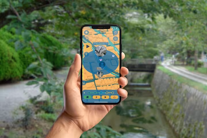Hand holding smartphone displaying interactive map app for self-guided walking tour in Kyoto park