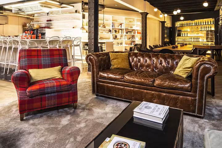 Chic designer loft with leather sofa and plaid armchair, ideal for La Boqueria Market Tour and Premium Cooking Class.