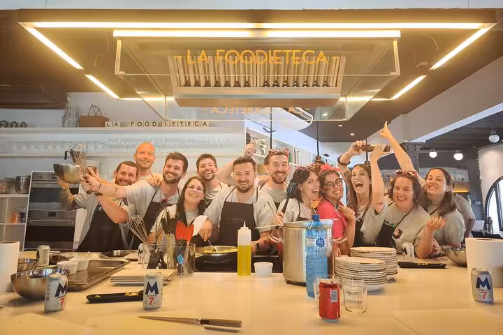 Happy group at La Boqueria Market cooking class, showcasing culinary skills in a vibrant designer kitchen loft.