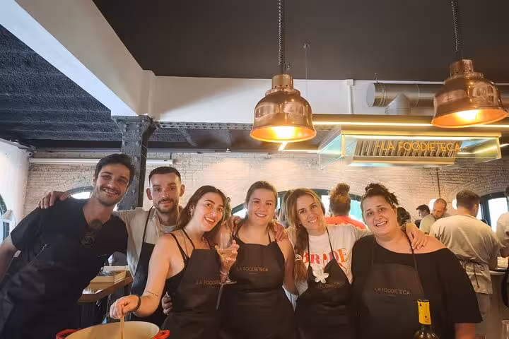 Smiling participants enjoying La Boqueria Market cooking class experience in a stylish designer loft kitchen.