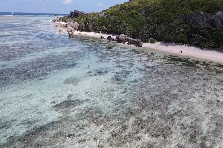 Crystal-clear waters and pristine beach at La Digue, ideal for exploring on a private full-day tour.