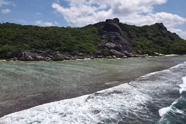 Breathtaking rocky shoreline and lush greenery in La Digue, highlighting natural beauty on a private tour.
