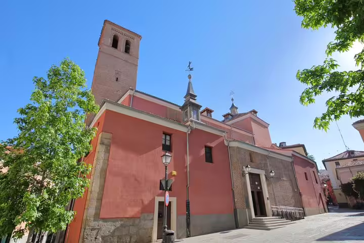 Historic pink church with bell tower on a sunny street in La Latina neighborhood, Madrid