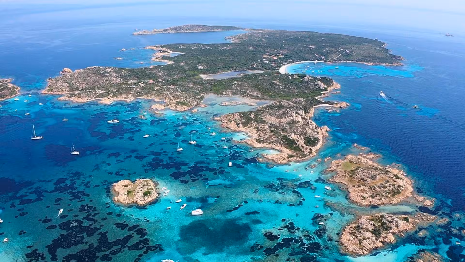 Aerial view of the stunning turquoise waters and lush islands of La Maddalena archipelago, ideal for a wooden boat tour.