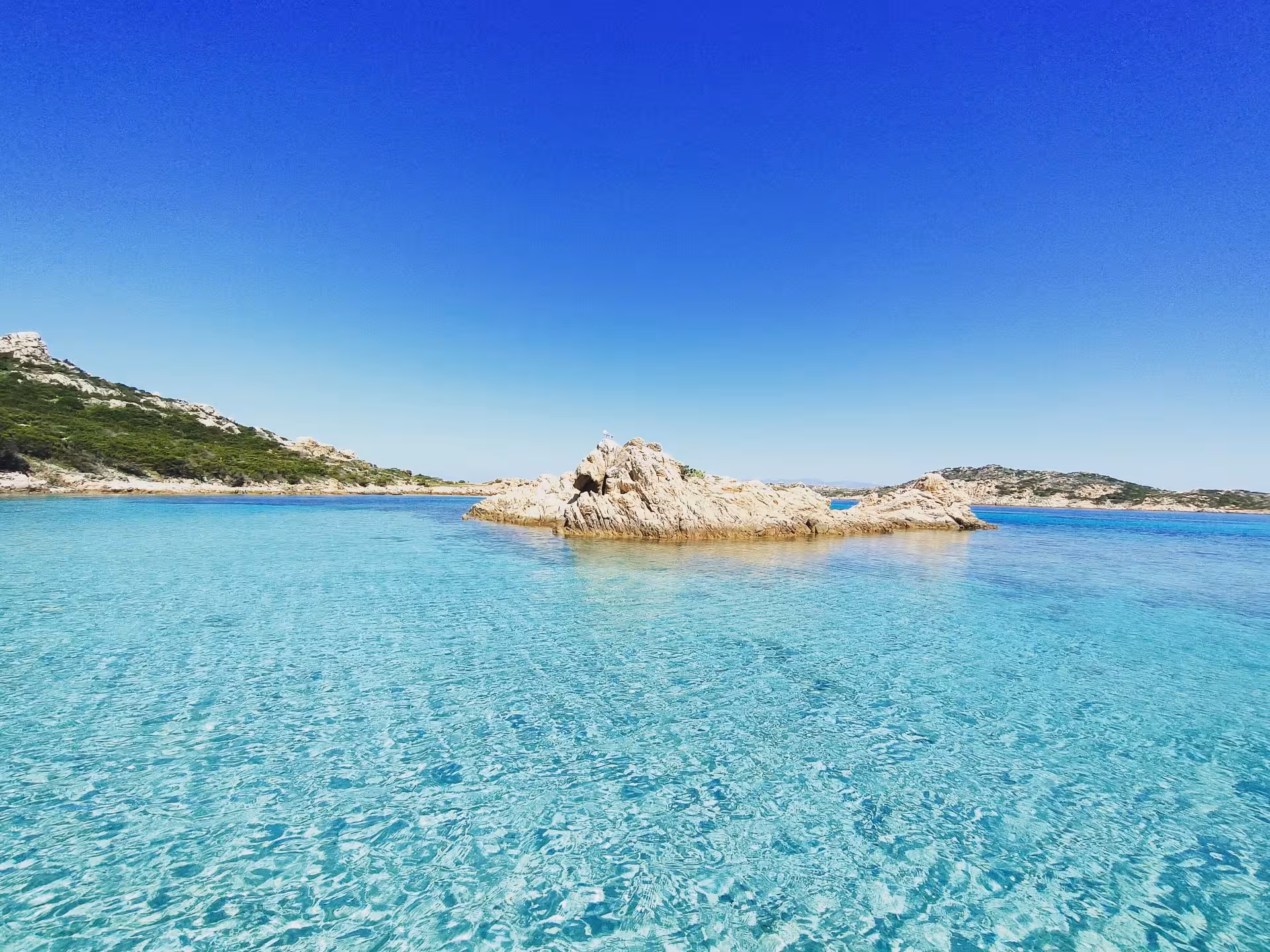 Pristine turquoise waters and rugged rock formations in La Maddalena Archipelago, ideal for a serene boat trip experience.
