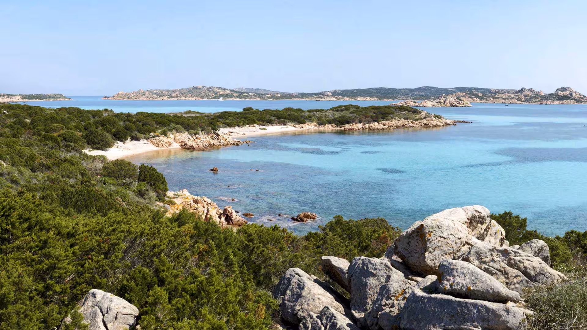 Scenic view of a pristine beach and turquoise waters in the La Maddalena Archipelago, ideal for a motorboat tour.