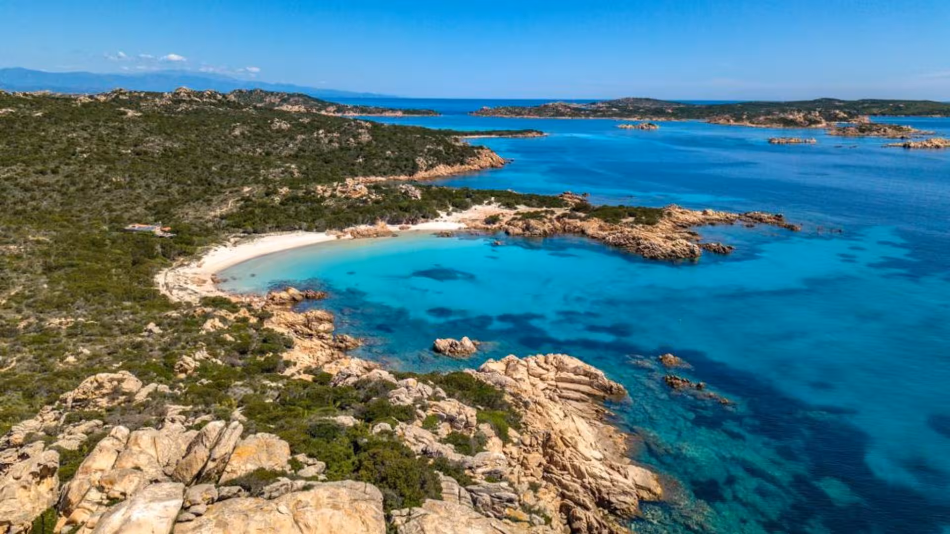 Aerial view of pristine beach and turquoise waters in the La Maddalena Archipelago, perfect for speedboat tours.