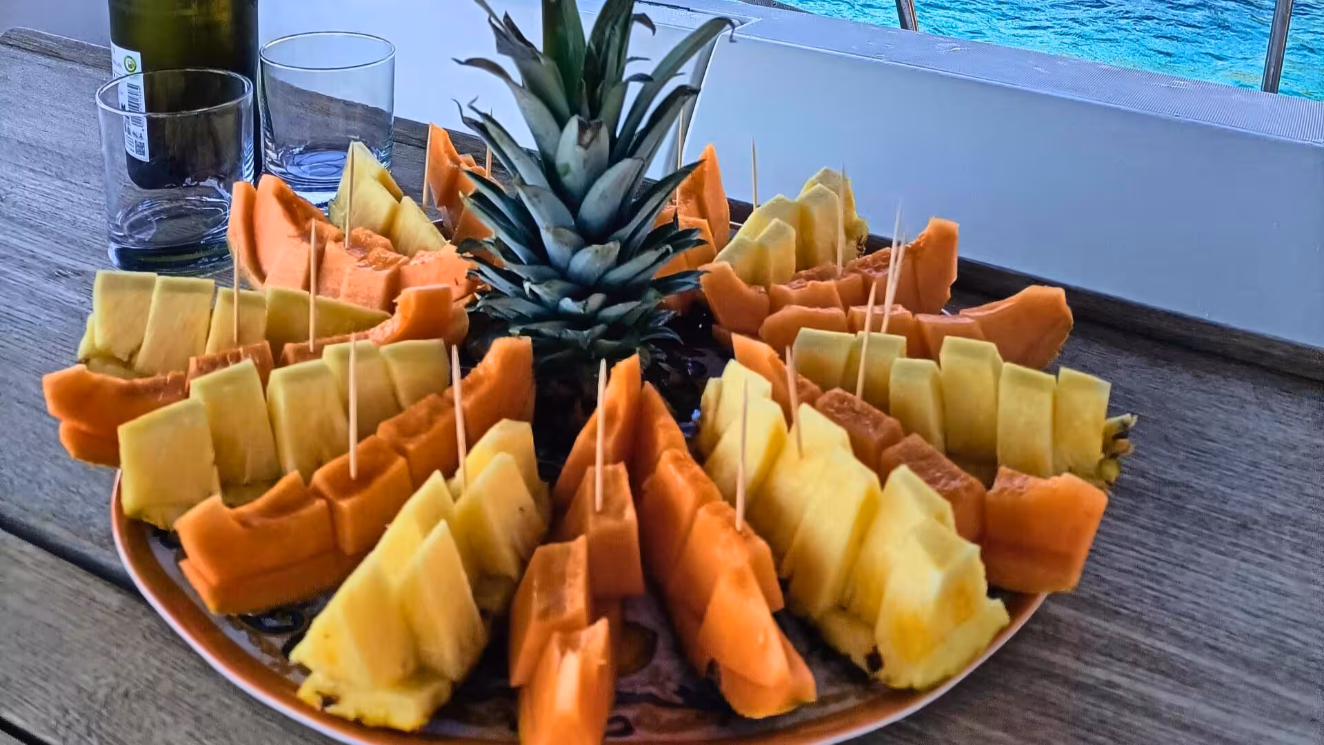 Enjoy vibrant tropical fruits like pineapple and papaya on a catamaran deck during the La Maddalena archipelago tour.