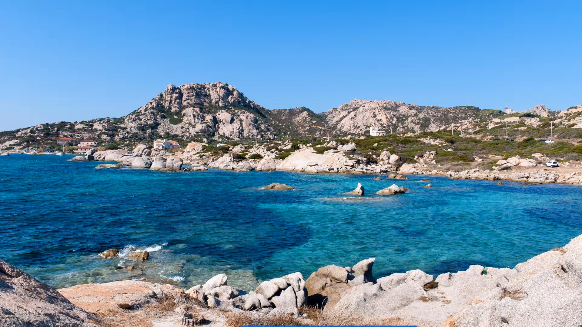 Scenic view of La Maddalena coastline with clear blue waters and rugged cliffs, perfect for a Palau minibus tour.