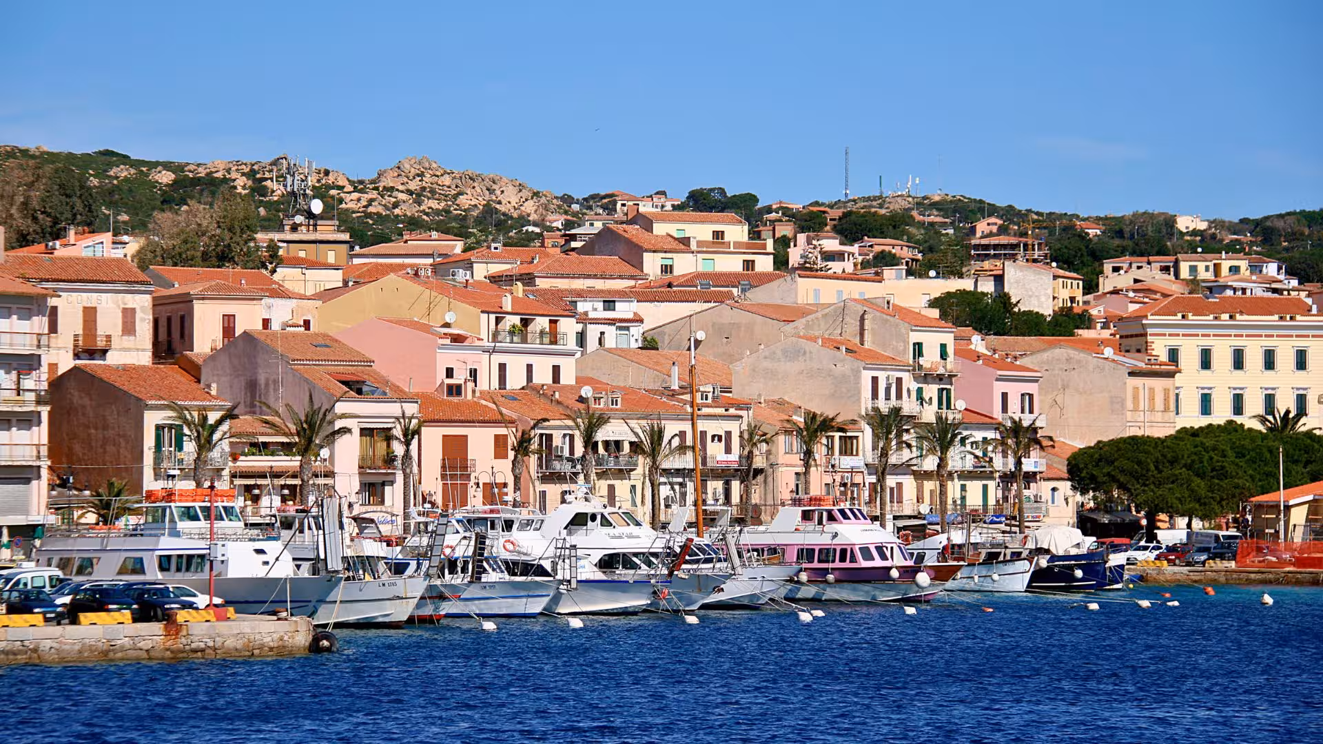 Colorful coastal buildings and boats in the picturesque harbor of La Maddalena, Sardinia.
