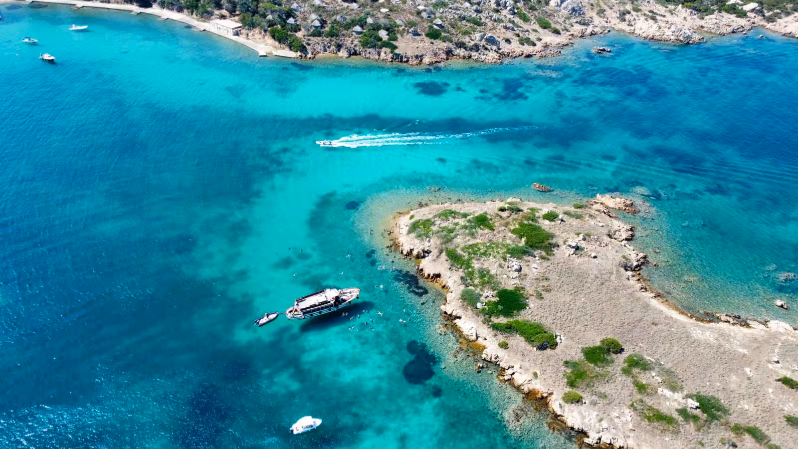 Aerial view of boats navigating the turquoise waters around the scenic islands of the La Maddalena Archipelago.