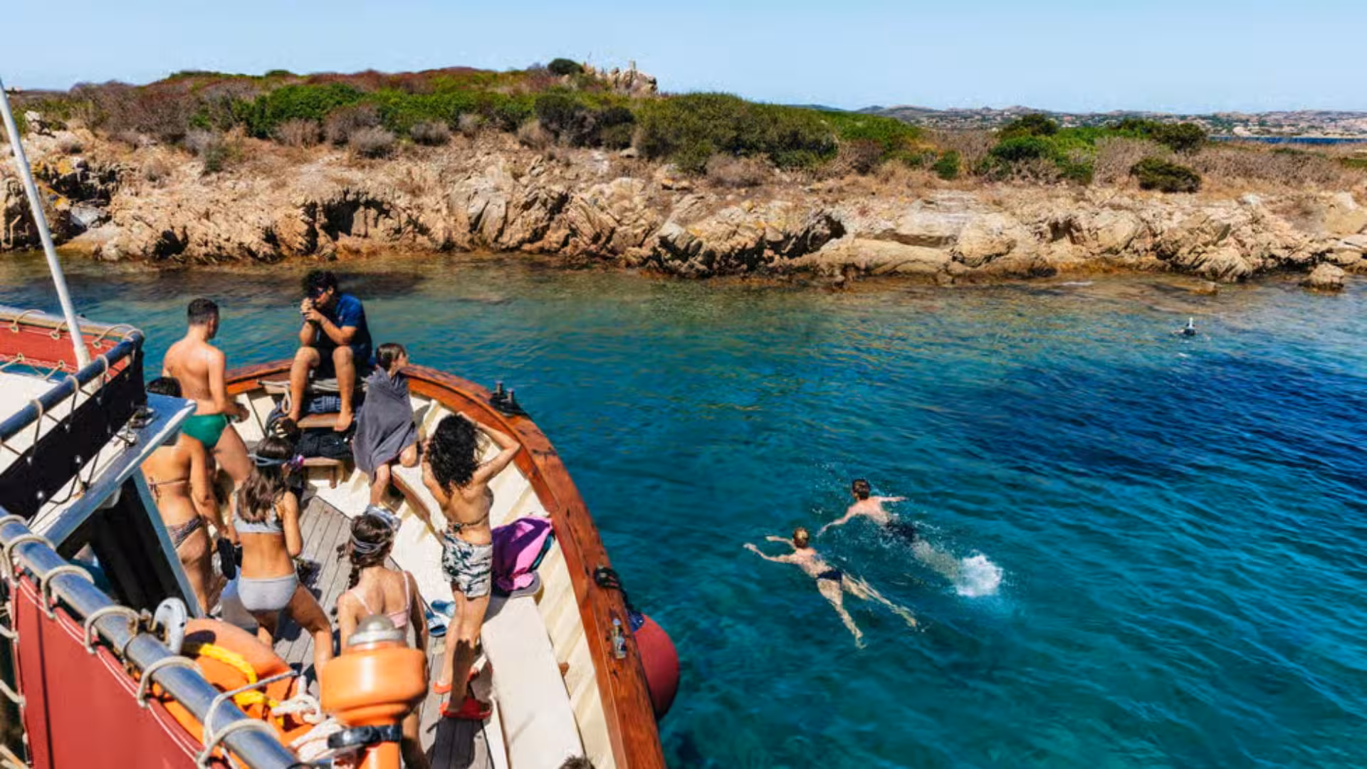 Visitors enjoy swimming in crystal-clear waters during a motorboat tour of La Maddalena Archipelago.