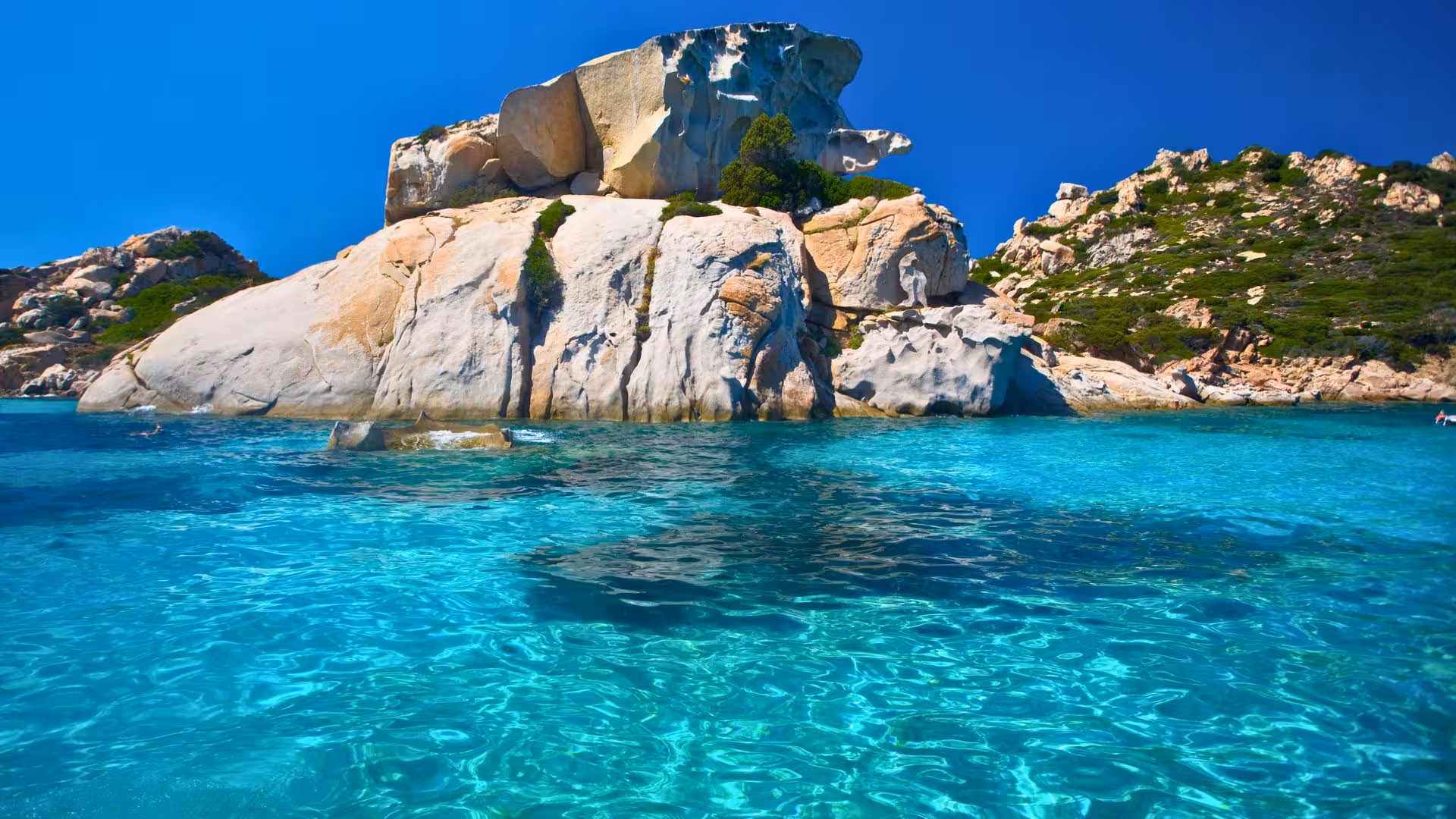 Close-up of a rocky coastline with crystal-clear waters in La Maddalena, perfect for exploring on a dinghy tour.