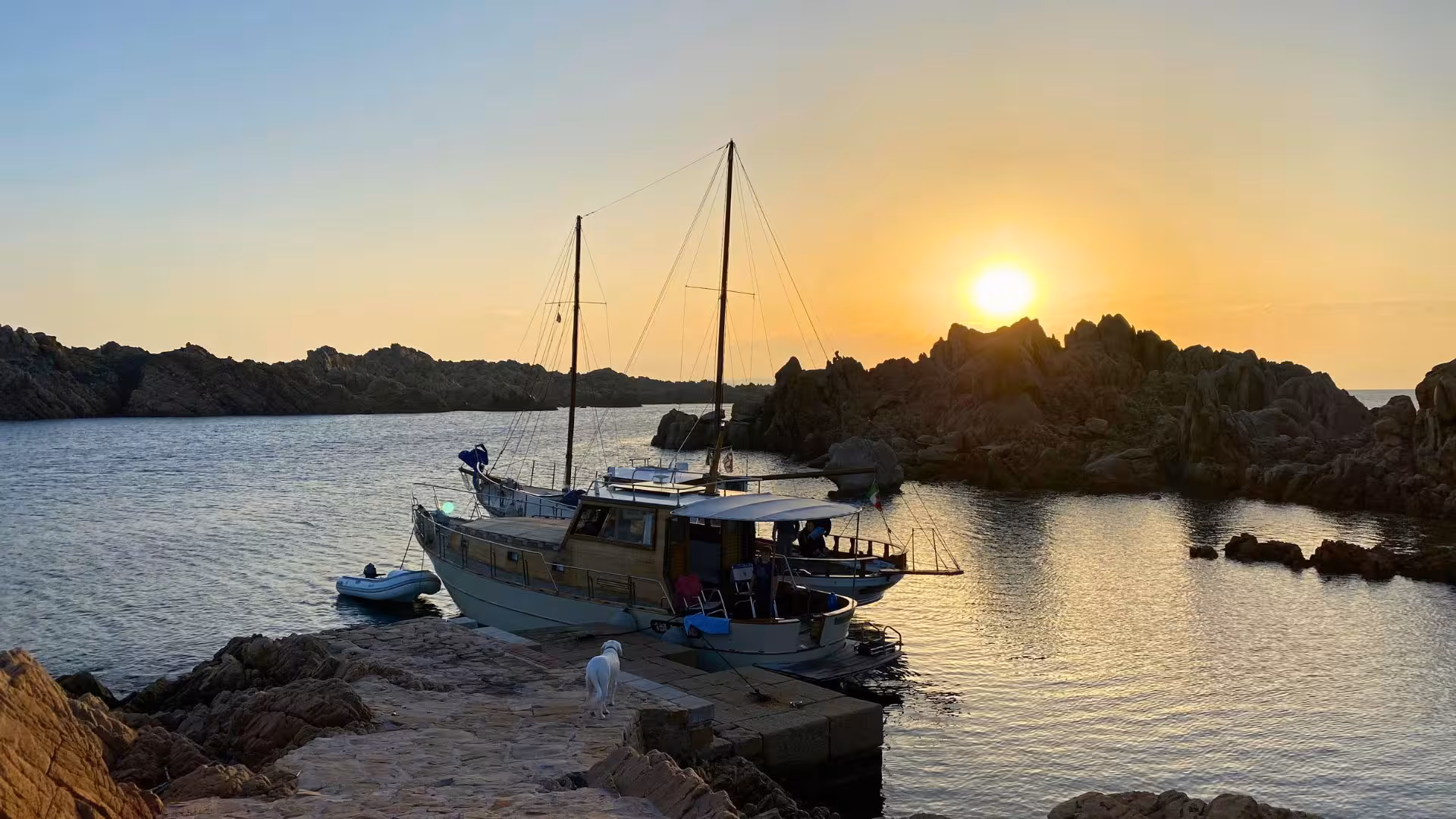 A sailboat docked at sunset in the serene La Maddalena Archipelago, ideal for a private evening tour in Sardinia.