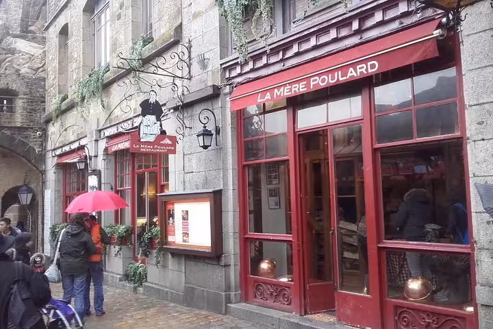 La Mère Poulard restaurant facade at Mont-Saint-Michel with red awning and stone buildings