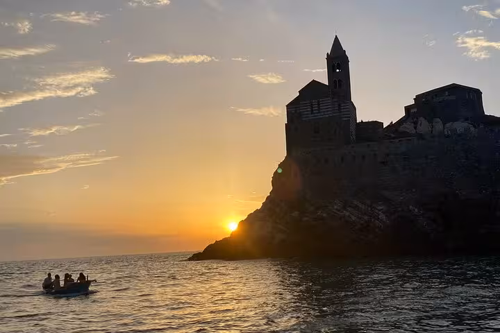 Silhouette of a historic building at sunset with a small boat in the foreground near Portovenere, La Spezia tour.