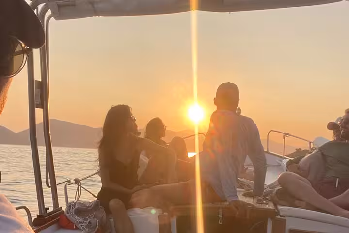 Tourists enjoy a stunning sunset view over the sea on a boat during the La Spezia 3-hour Portovenere tour.