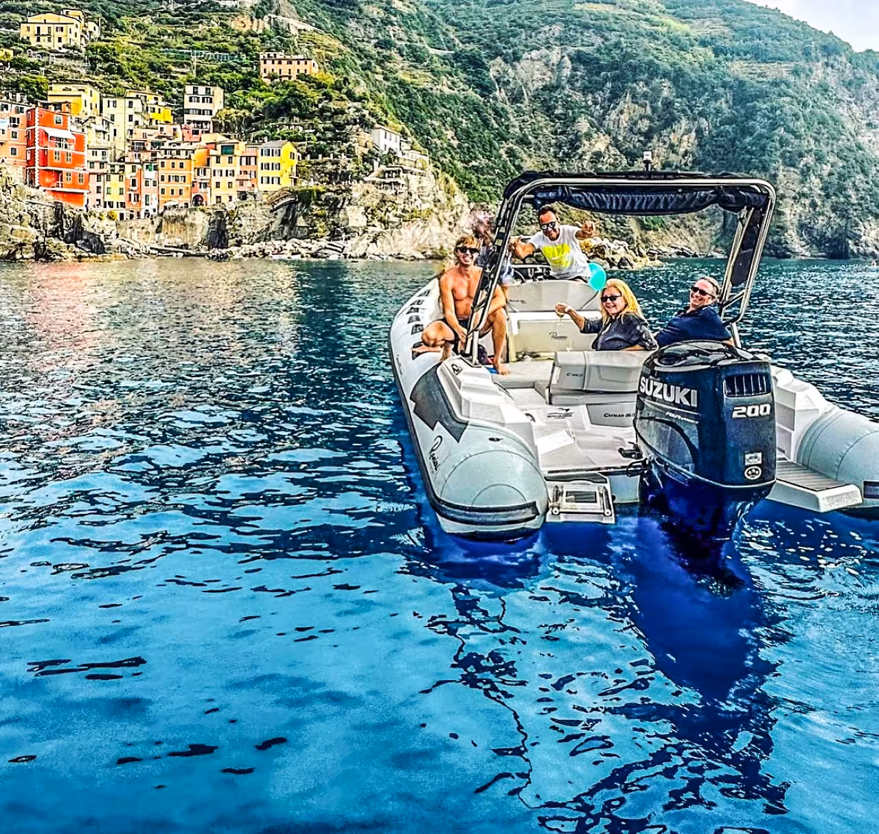 Small group speedboat near Riomaggiore on a Cinque Terre full-day boat tour from La Spezia, colorful cliffside homes