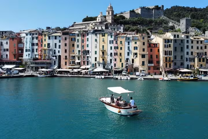 Charming pastel buildings and a boat on the turquoise waters of Portovenere seen during the La Spezia tour.