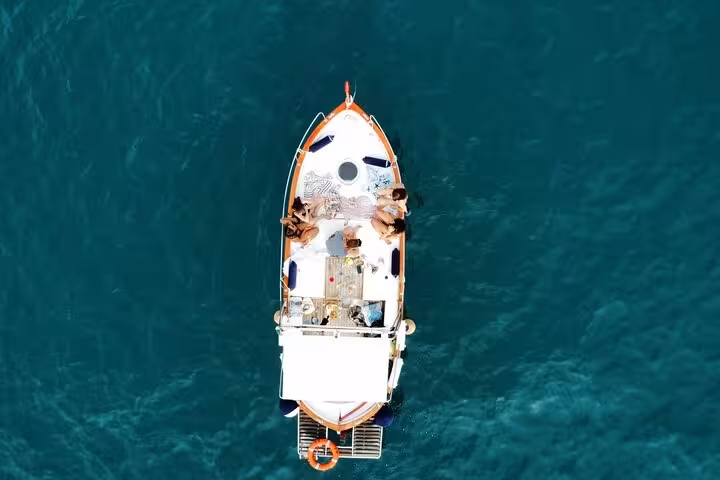 Aerial view of a boat cruising the turquoise waters of Golfo Dei Poeti, offering a unique sunset experience.