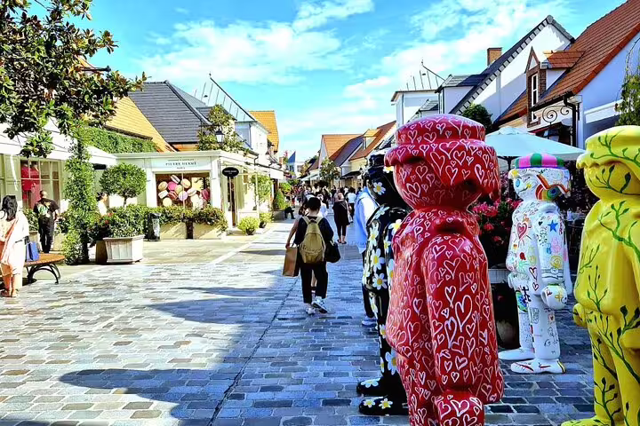 La Vallée Village outlet street near Paris with colorful Bearbrick statues, ideal for private round-trip transfer