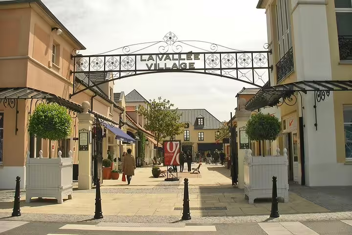La Vallée Village outdoor shopping promenade with decorative iron archway entrance near Paris