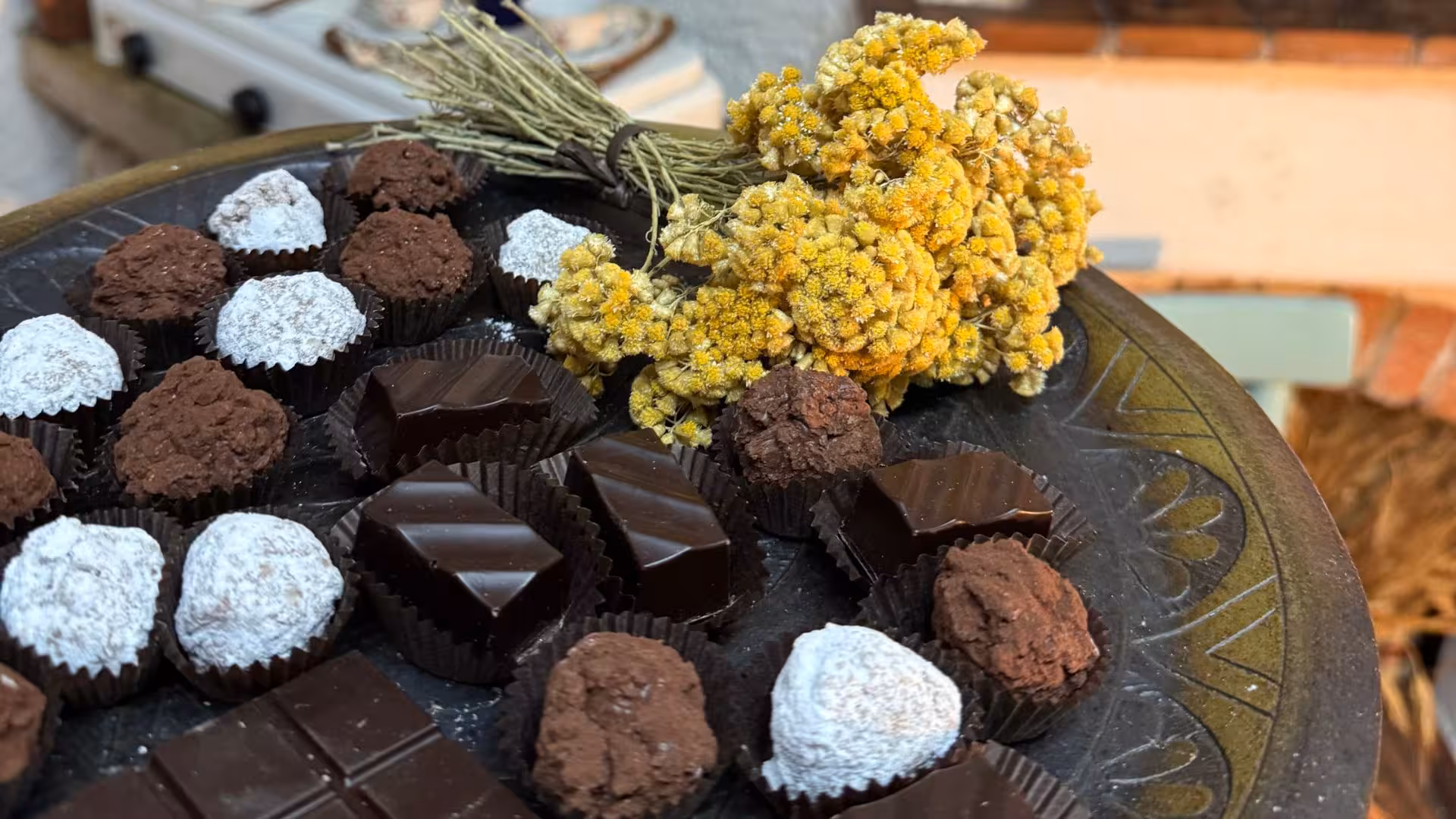 Assorted artisanal chocolates with rustic herbs on display for Laconi chocolate tasting and liqueur tour.
