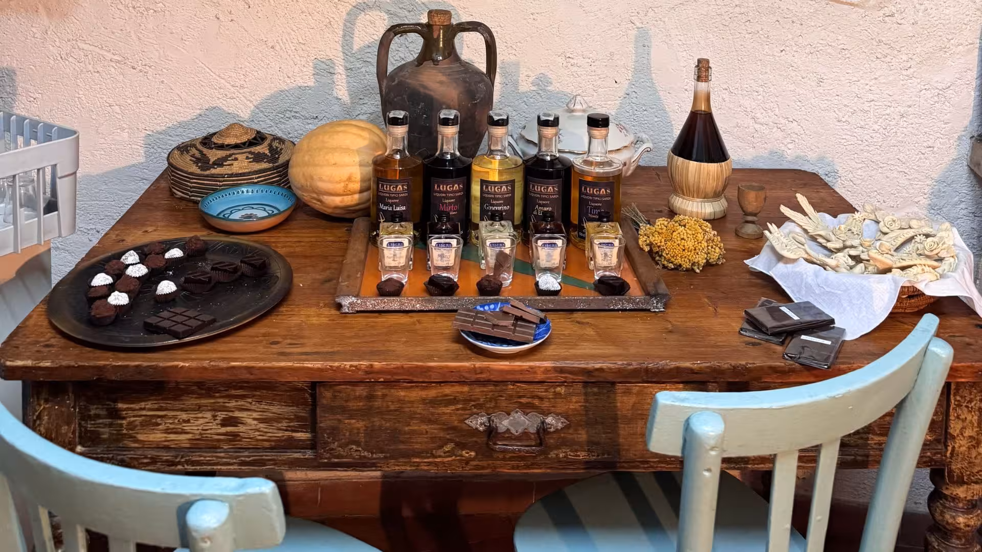 Elegant wooden table with assorted chocolates and liqueurs, showcasing Sardinian flavors on Laconi tasting tour.