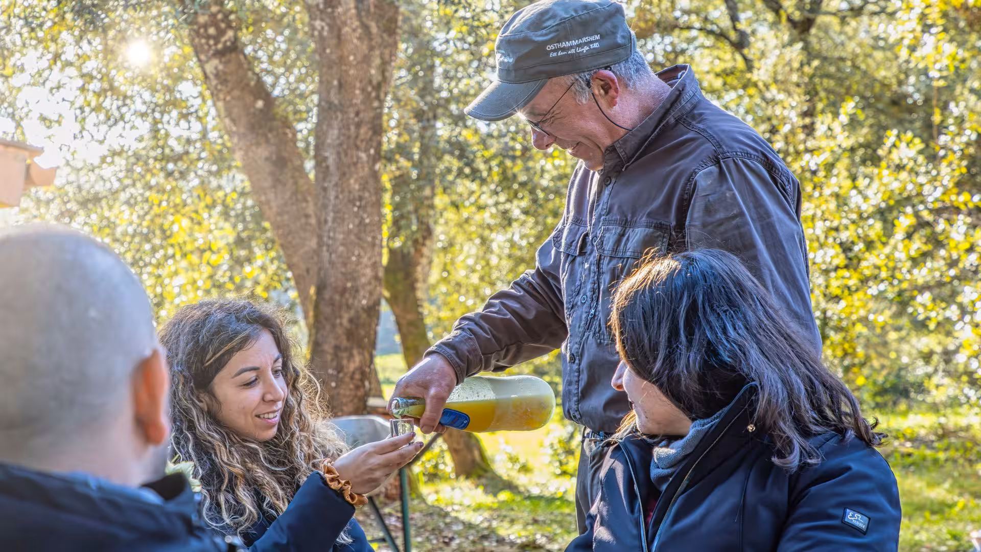 Guide serving drinks to guests during Laconi truffle hunting excursion with lunch under the trees.