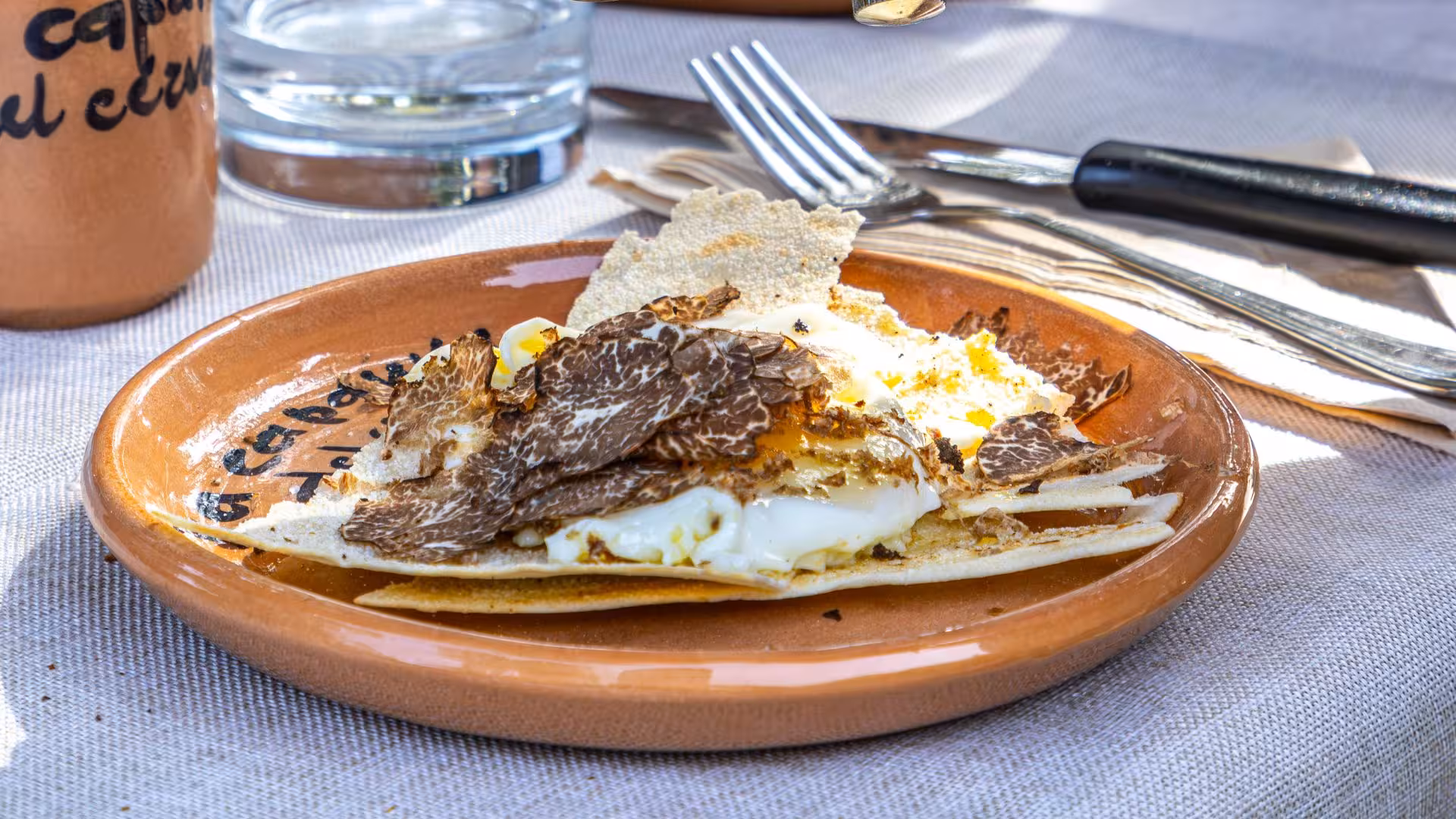 Gourmet dish featuring shaved truffles on eggs, showcasing Laconi's culinary delights during truffle hunting tours.