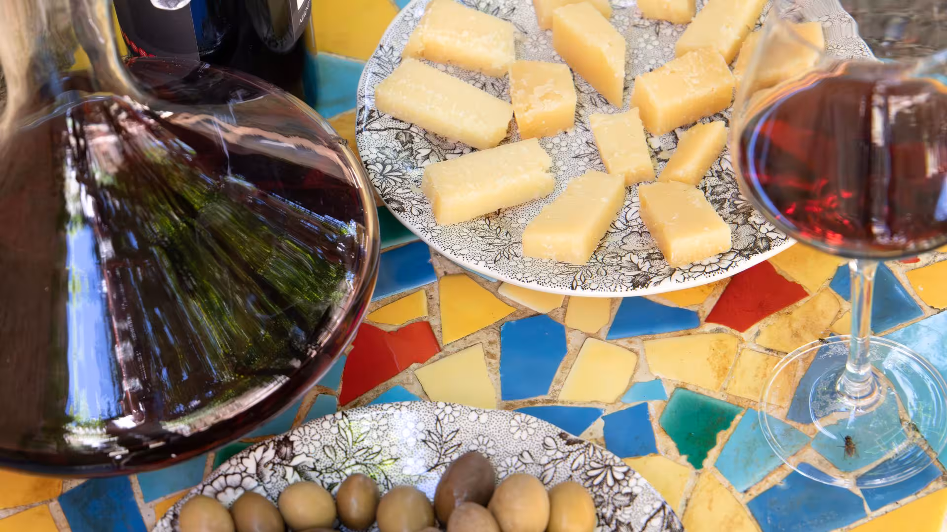 Close-up of wine, cheese, and olives on a colorful table at a Laconi winery tasting event in Sardinia.