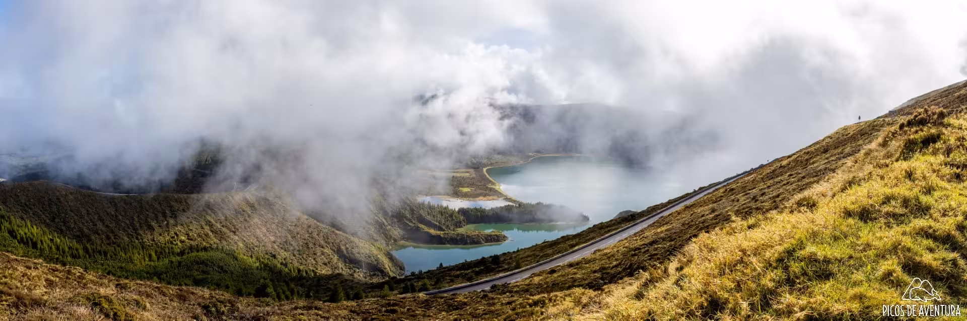 Cloudy panoramic view of Lagoa do Fogo crater lake and road, São Miguel van tour combo with dolphin swim
