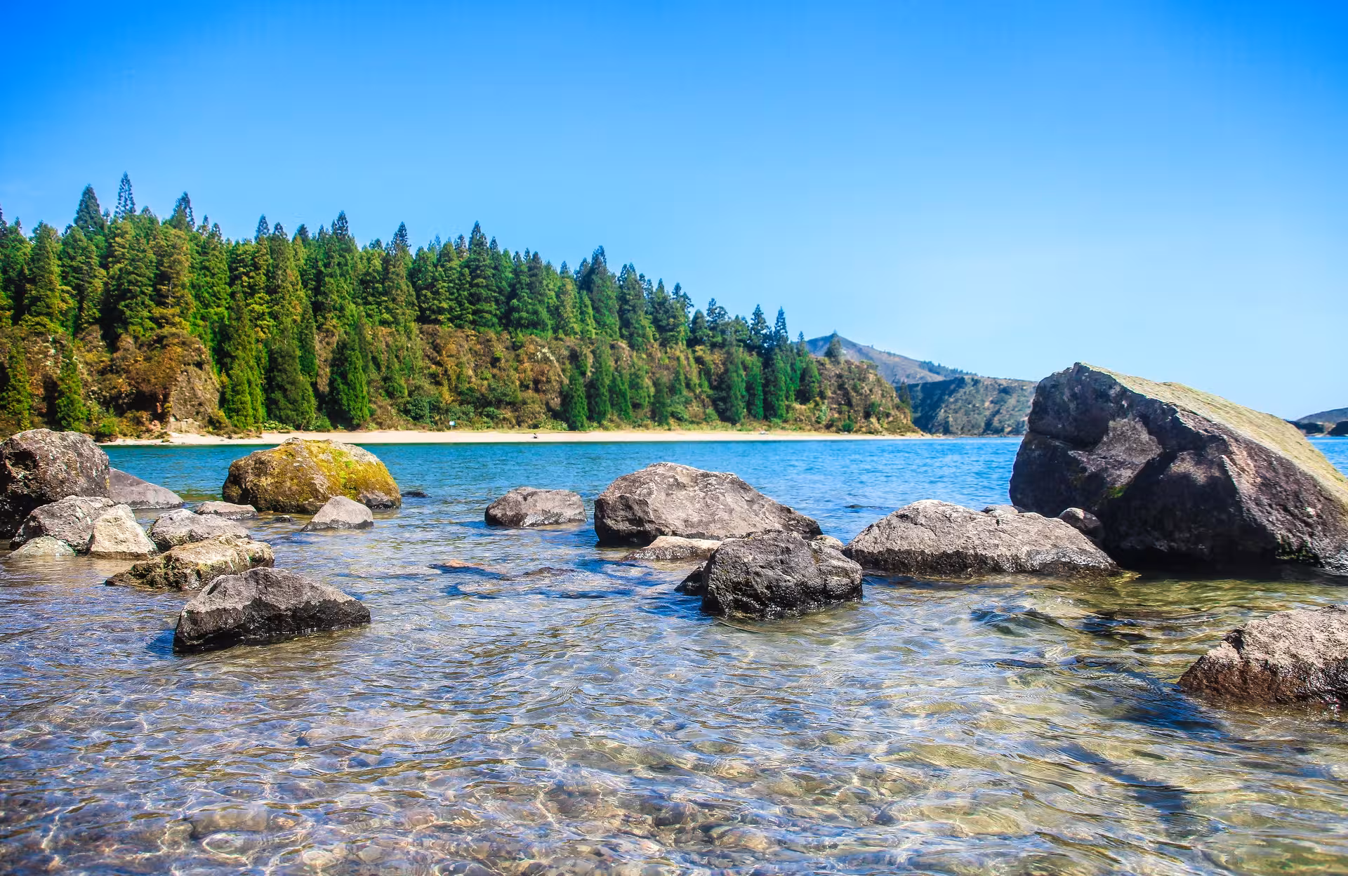 Clear waters and volcanic rocks at Lagoa do Fogo, São Miguel Azores, scenic stop on guided hike tour