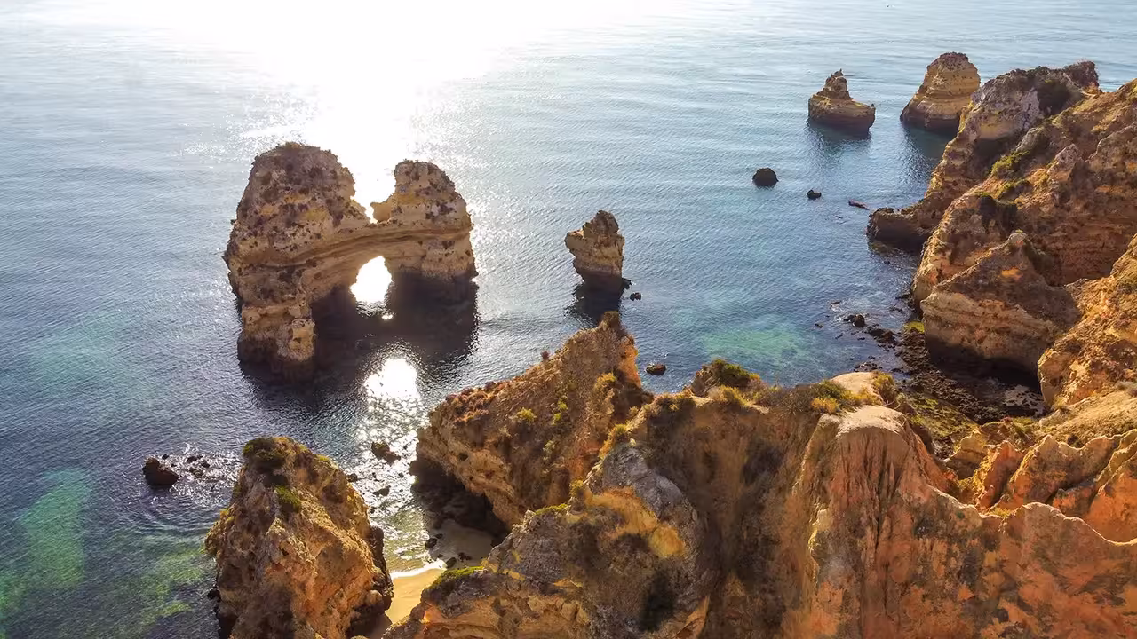 Stunning aerial view of golden limestone rock arches and sea stacks along the Lagos Algarve coastline tour