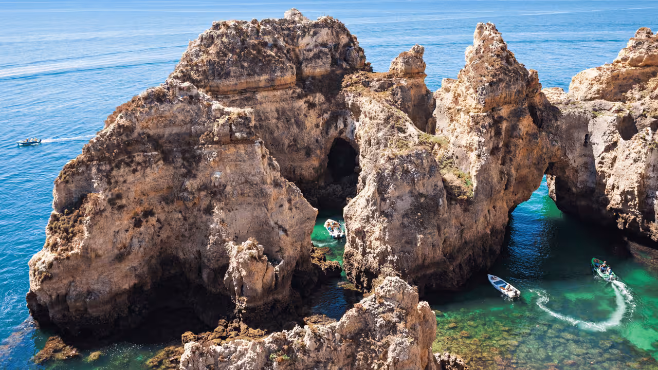 Aerial view of boats exploring emerald green grottos and sea caves at Ponta da Piedade Lagos boat tour