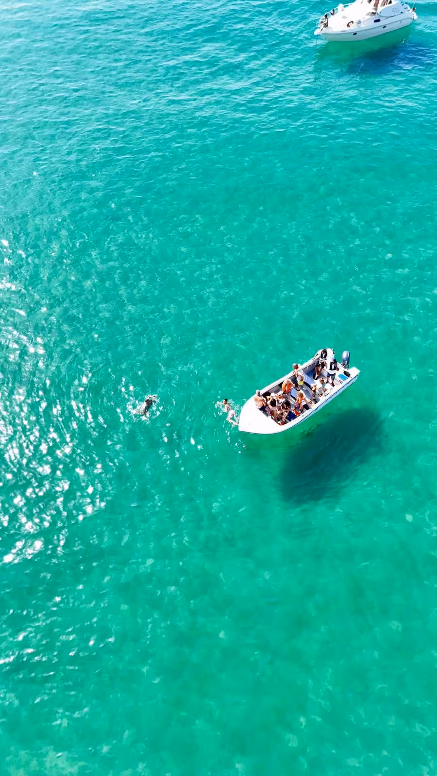 Aerial view of Lagos boat tour with swimmers enjoying crystal clear turquoise Atlantic waters at Ponta da Piedade Algarve