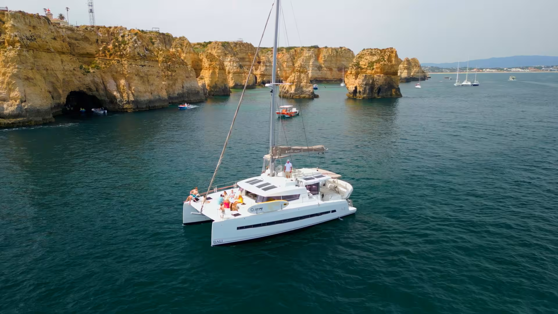 White catamaran sailing by Ponta da Piedade cliffs in Lagos on a full-day Algarve cruise with sea caves