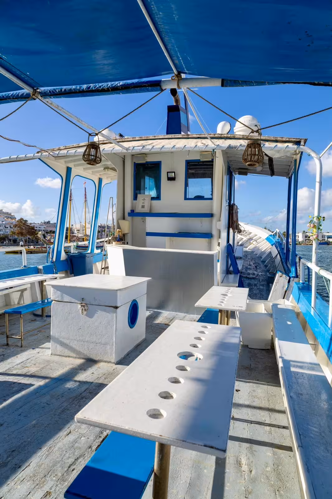 Open deck of a blue and white Lagos coastal brunch cruise boat with seating and shaded canopy on sunny day