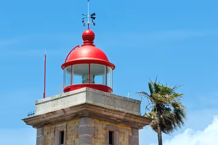 Vibrant red lighthouse against a clear blue sky in Lagos, ideal for scenic views on a private city walking tour.